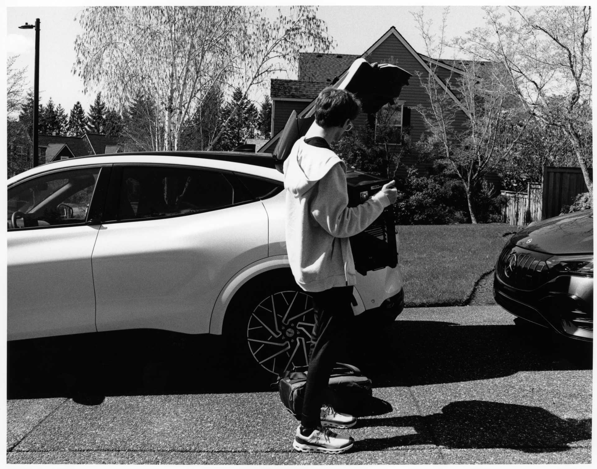 Black and white photo of me loading something into the trunk of a car.