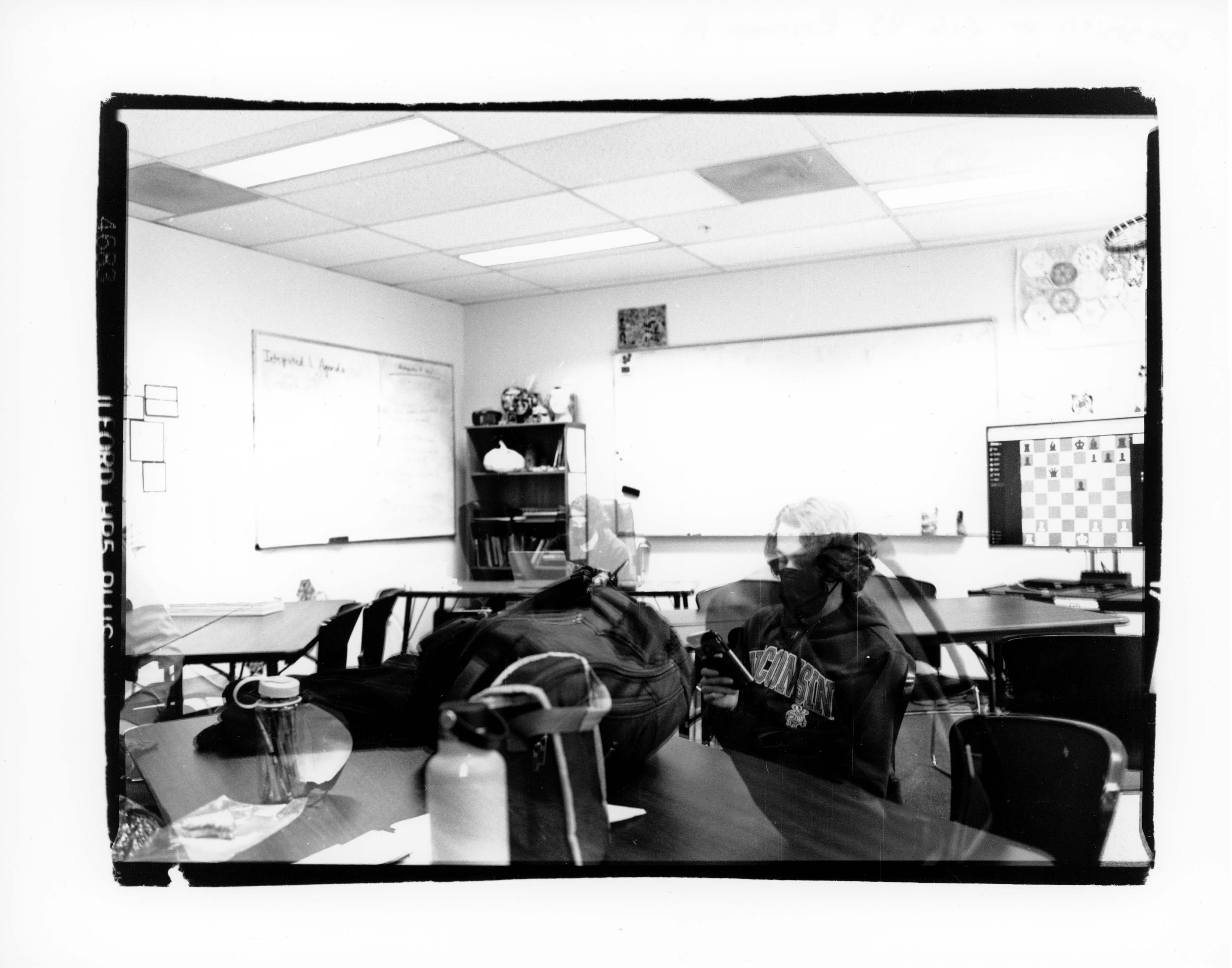 Black and white double exposure of a classroom with two transparent people.